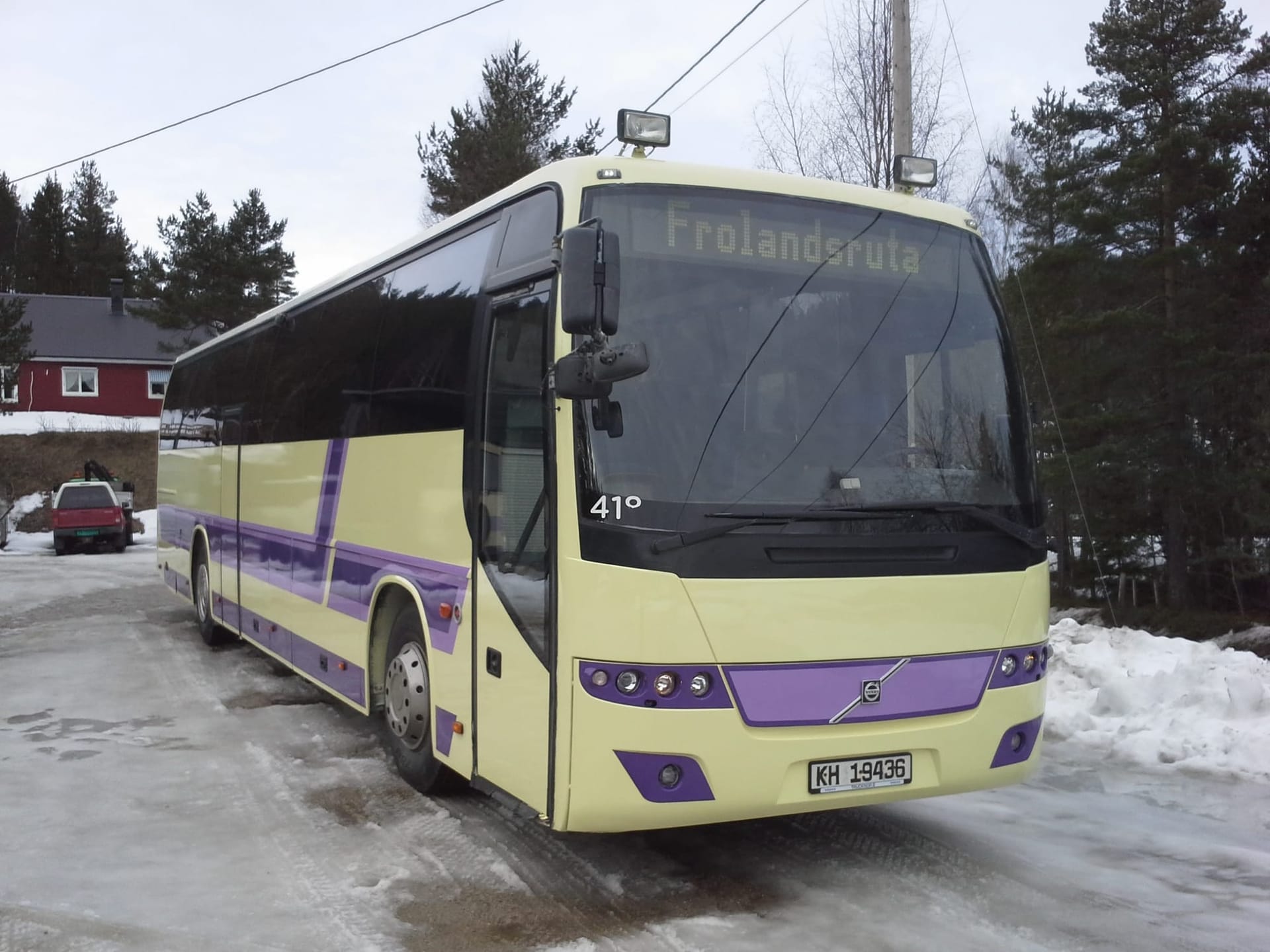 Frolandsruta-buss i krem og lilla foran snødekte trær