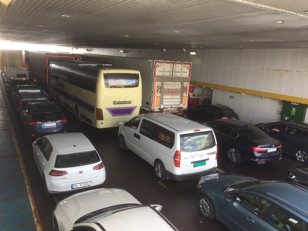 Bussen står på bildekket i en ferge mellom personbiler