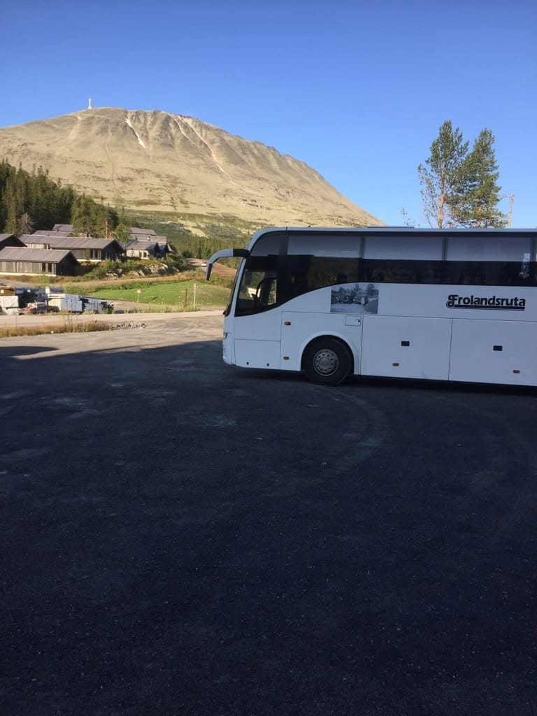 Bussen parkert under et fjell med hytter i bakgrunnen