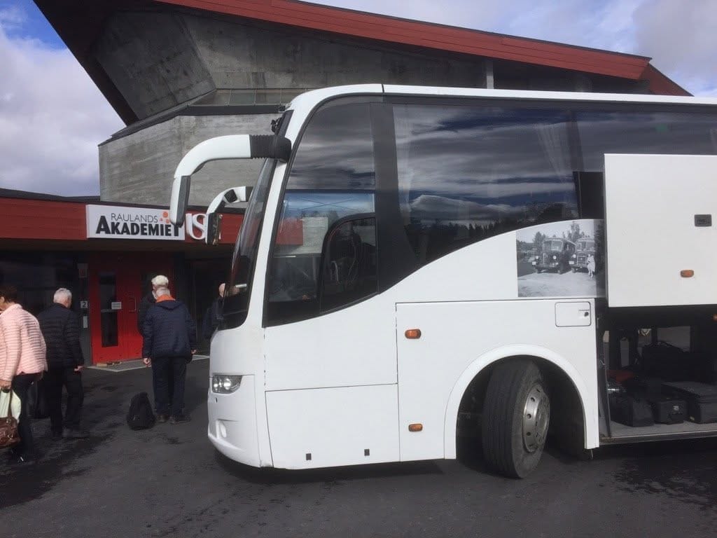 Reisende går om bord i bussen ved et inngangsparti
