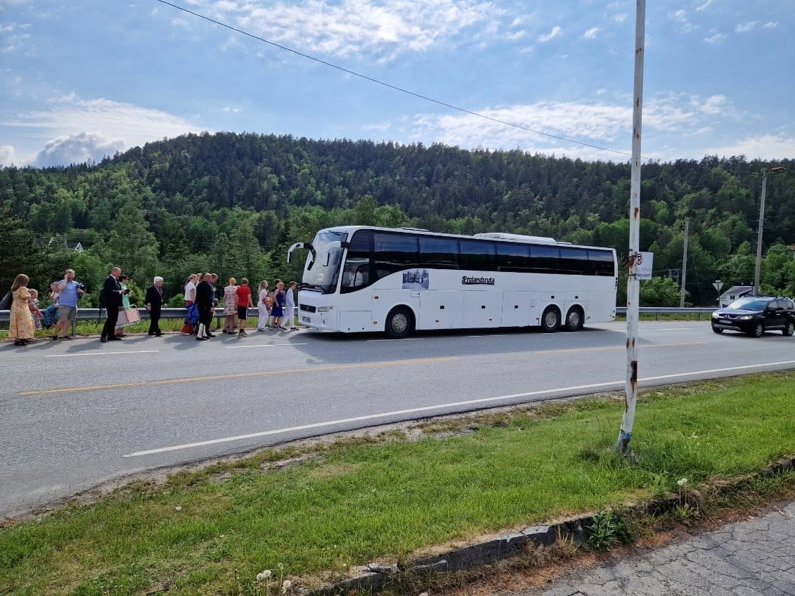 Et reisefølge går mot bussen langs en landevei