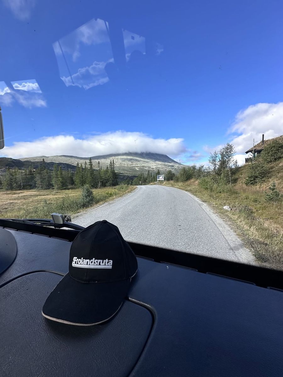 Frolandsruta-caps på dashbordet med fjellvei foran frontruta