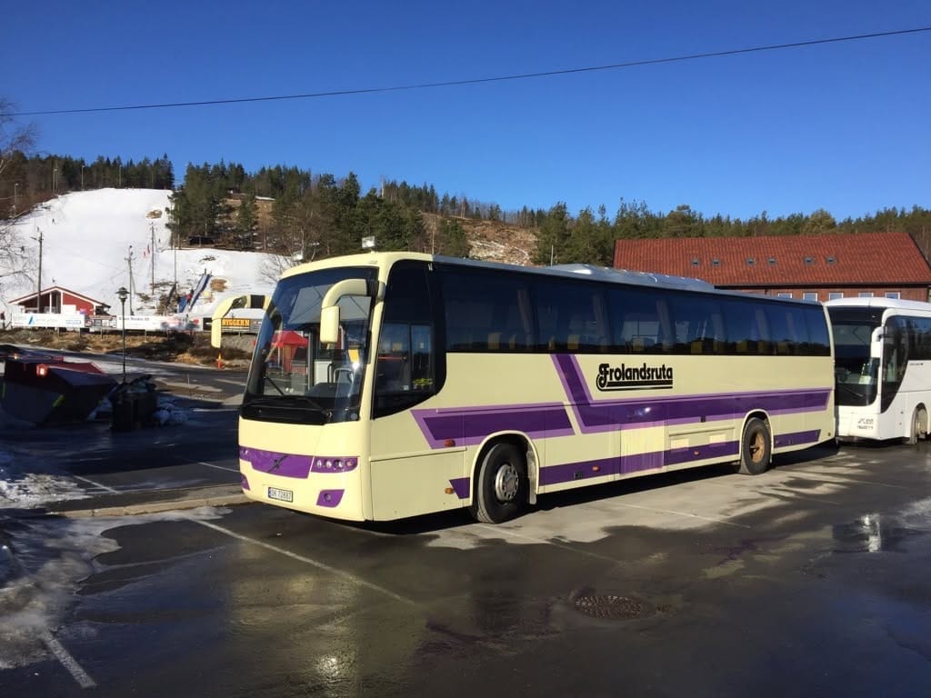 Frolandsruta-bussen parkert i vintersol med snø på bakken